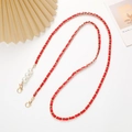 Detalle de la cadena tejida en cuero rojo con cierres dorados y perlas de imitación - Rojo