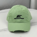 Détail de la casquette vert menthe avec broderie noire et texture déchirée effet usé - vert clair