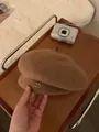 Brown wool beret with a gold JM logo detail, styled on a wooden tray with a vintage look - Caramel color