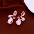 Détail de boucles d'oreilles goutte en cristal rose avec monture dorée et strass - Rose
