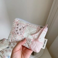 Hand holding a mini quilted floral coin purse with a pink zipper and woven label detail - Checkered Floral Rabbit