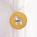 Detail of wooden curtain tieback with yellow Dala horse motif on white linen rope - Yellow Trojan Horse