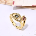 Anello dorato regolabile con occhio azzurro e cuore di zircone rosa su sfondo bianco - Stile Cuore Occhio Blu