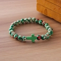 Beaded bracelet with turquoise cross pendant and multicolored stone beads on wood - Green White Red Spotted Turquoise Cross