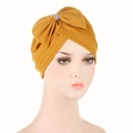 Detail of yellow turban hat featuring a large rhinestone bow on textured fabric - Turmeric