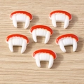 Vista piatta di ciondoli in resina a forma di denti di vampiro per DIY su sfondo legno - Dente