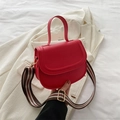 Red PU leather shoulder bag with green striped strap on white blazer background - Red
