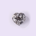 Polished heart-shaped natural stone with black and white spotted texture on lavender background - Granite