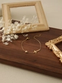 Close-up of golden cross bracelet with zircon stone on a rustic wooden display - Cross Zirconia Bracelet (ZHB1147 Gold)