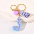 Detailed macro view of purple initial J keychain with heart sequins and tassel - Letter J