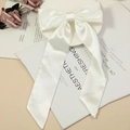 Elegant white satin hair bow with long ribbons and smooth glossy silk texture - White