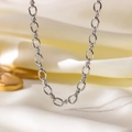 Detailopname van een zilveren gelaagde schakelketting op een beige zijden achtergrond - Halsketting (H652) / Staalkleur