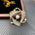 Détail macro d'une broche spirale dorée vintage avec perle blanche et strass brillants - BZ038 Spirale Dorée