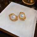 Dettaglio ravvicinato di orecchini a fiore placcati oro con perla in una scatola - Clip per Orecchie a Perla Tonda con Texture Lavica Irregolare / Oro
