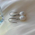 Elegant S925 silver hook earrings featuring white freshwater rice pearls on silk background - Silver