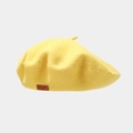 Detailed close-up of a yellow wool beret featuring a vintage brown leather logo patch - Bright Yellow