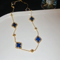 Macro detail of gold plated necklace with blue clover motifs and intricate bead edging - Blue Zirconia Flower
