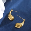 Detalle de pendientes dorados con textura de ondas sobre un fondo azul oscuro - Estilo B (Gota Aerodinámica) / Dorado