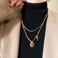 Close-up of double-layered gold tiger eye sun pendant necklace on a beige blazer - Stacked Cross Tiger Eye Pendant (13# Necklace-Gold)