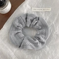 Close-up of gray knitted hair scrunchie with herringbone pattern on textured paper - Gray