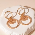 Vista de primer plano de pendientes dorados con perlas y diseño de doble C cruzada - Estilo de Círculo de Perlas Doradas