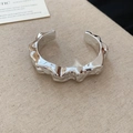 Dettaglio del bracciale a fascia argento irregolare su un tessuto di lino beige testurizzato - Stile Pieghettato a Onde Irregolari Argento (9#)