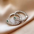 Macro shot of silver snake-shaped earrings with green gemstone eyes on champagne silk - 7# Zirconia Snake Shape Green Eye Studs