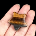 Polished tiger eye stone star carving with golden chatoyancy held in hand - Tiger's Eye