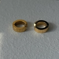 Primo piano di orecchini a cerchio dorati con strisce verticali e finitura metallica lucida - Ear Cuff a Righe