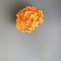 Artificial orange hydrangea flower stem with green plastic branch on gray backdrop - Orange