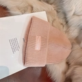 Detalle del gorro de punto rosa con etiqueta bordada THE FOCUS sobre fondo de felpa suave - Estilo de etiqueta de letra / Rosa