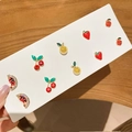 Vista detallada de cinco pares de pendientes de frutas con brillantes en cartón blanco - Juego de 10 piezas serie de frutas (pasador de acero inoxidable)