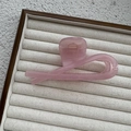 Gros plan d'une pince à cheveux rose translucide au design minimaliste torsadé - Rose Gelée