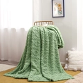 Sage green fleece blanket with cable knit texture draped over a chair in a cozy room - Matcha Green