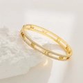 Detailed macro view of gold-plated bangle with Roman numeral cutouts and paved zircons - Gold Men's