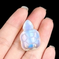 Miniature opalite turtle carving with iridescent blue glow held in hand - Opal (Synthetic)
