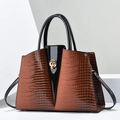 Detailed close-up of brown crocodile texture and gold metal twist lock on tote bag - Earthy Yellow