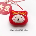 Detail of red plush lion brooch with embroidery and Great Luck apple tag decoration - Fortune Baby