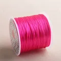Macro detail of bright pink elastic beading cord wound on a white plastic spool - Rose Red