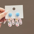 Dettaglio di orecchini natalizi in acrilico a forma di U con motivi festivi colorati - Blu