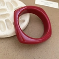 Macro view of wide red acrylic faceted geometric bangle with a high-gloss resin finish - Rounded Square Style / Burgundy