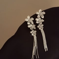 Detail view of silver floral tassel earrings with sparkling rhinestones and metal finish - Silver