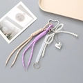 Nahaufnahme der lila und beigen Web-Schlüsselanhänger mit Perlenbogen und Herzanhänger - Lila/Beige (K4665)