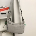 Light grey nylon messenger bag with large front pocket and green zipper detail - Gray