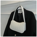 Detail of white wave embossed leather texture on shoulder bag over a black blazer - White