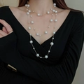 Elegant multi-layered long pearl necklace with golden chains on a black V-neck top - Extra Long Pearl Necklace