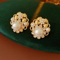 Dettaglio di orecchini vintage a fiore con perle e cristalli su scatola in velluto - Stile Fiore Oro