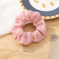 Pink fabric hair scrunchie with gold heart patterns on a rustic wooden background - Pink