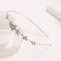 Detalle de diadema de flores doradas con pedrería y perlas blancas sobre fondo blanco puro - Flor Dorado