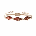 Detail eines handgewebten Armbands mit gefleckten Muscheln und kleinen weißen Perlen - Geflecktes Rot